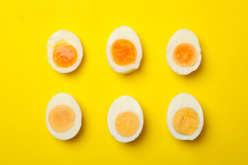 Hard boiled eggs on yellow background, top view