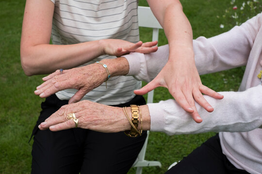 Therapist touching the oustretched arms of her client.