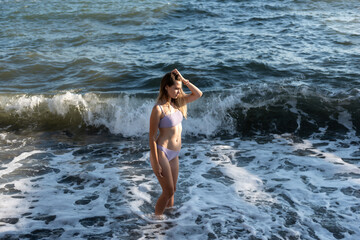 A young girl in a bikini bathing day in a stormy sea.