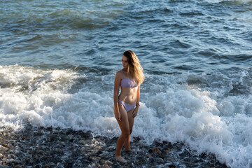 A young girl in a bikini bathing day in a stormy sea.