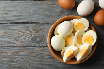 Bowl with boiled eggs on wooden background, top view