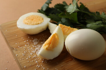 Board with boiled eggs, salt and parsley on brown background