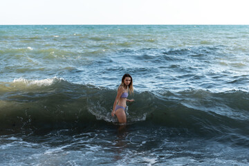 A young girl in a bikini bathing day in a stormy sea.