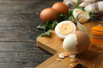 Board with boiled eggs, napkin and parsley on wooden background