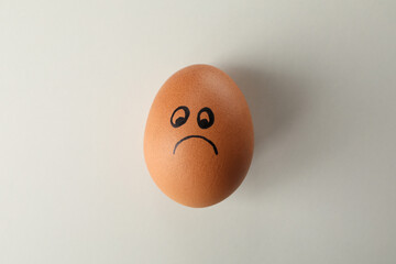 Boiled egg with sad face on white background