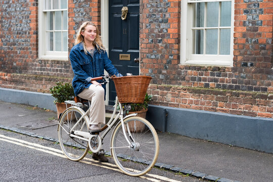 Young blond woman cycling down a village street.