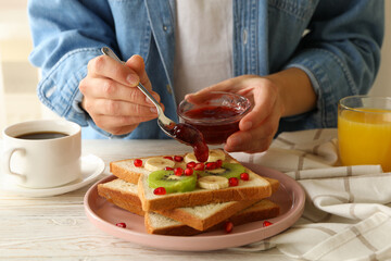 Obraz na płótnie Canvas Woman pour jam on tasty toast with fruits