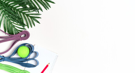 White background and resistance loop for exercise, notebook for workout plan and results, top view. Home workout plan concept while isolated. Minimal design, layout with copy space