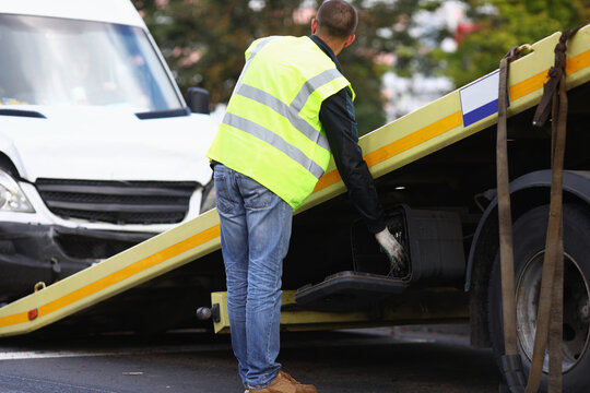 Tow truck driver loads wrecked minibus onto tow truck. Car evacuation services around clock concept