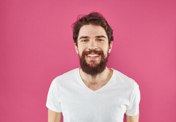 Handsome man with a beard and mustache on a pink background in a white T-shirt