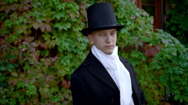 Handsome Young Man Wearing A Frock-Coat And A Top Hat Taking Off His Face Mask