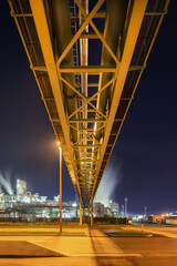 Night scene with illuminated petrochemical production plant and pipeline overpass, Antwerp, Belgium.