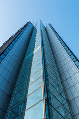 Looking up a tall glass and steel high-rise building..