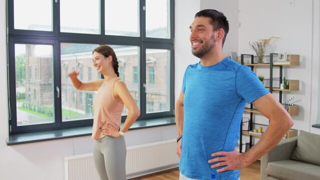 sport, fitness, lifestyle and people concept - smiling man and woman exercising and stretching at home