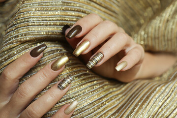 Fashionable manicure with a matte Golden color of nail Polish and brown on a long nail shape.