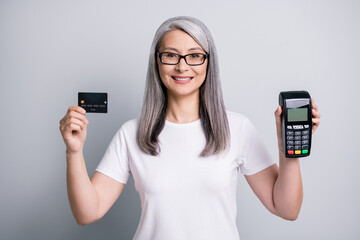 Photo of retired grandma hold debit card show terminal wear spectacles white t-shirt isolated grey color background