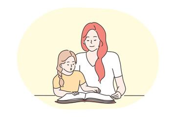 Happy leisure and activities at home with children concept. Young woman mother cartoon character reading, learning letters or words together with her small daughter at home. Relax, rest, family
