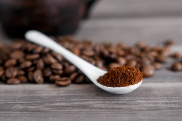  white ceramic spoon with ground coffee on a wooden background Fried Arabica grains.