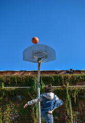 Young man playing basketball jumping towards the basket.