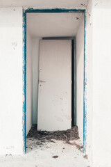 White door with blue frame on abandoned structure.