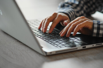 Close-up of female hands typing on the keyboard work process, checkered shirt.