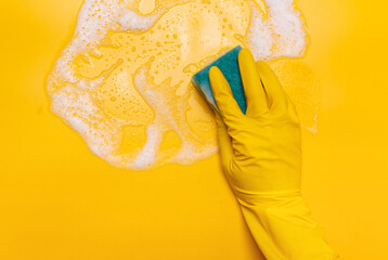  wipe the foam on a yellow background with a blue gloved sponge.