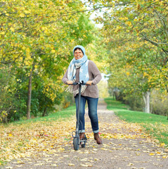 lachende Frau mit Roller im Park