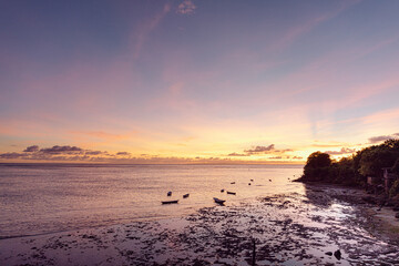Pink sunset on the ocean on a tropical beach in Bali with small fishing boats