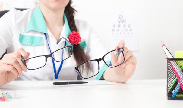 Doctor ophthalmologist holds in his hands two glasses for the eyes. The concept of choosing the right and comfortable modern glasses, copy space