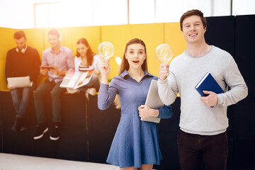 Two young people hold light bulb in their hands. 