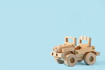 Wooden car toy on blue background with copy space for text.