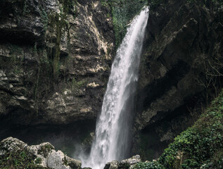 Fototapeta na wymiar Waterfall flowing from rocky stone wall