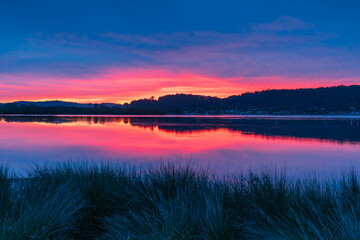 Reflection of Sunrise with soft high cloud over the waterfront