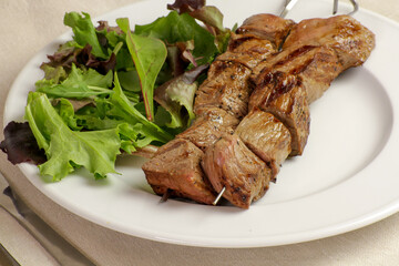 brochettes de boeuf grillées et salade dans une assiette