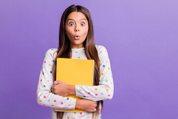 Photo portrait of amazed shocked girl hugging yellow book wearing sweater staring isolated on...