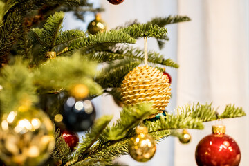 Christmas tree and decorations,eco, sparking, glowing balls. Happy New Year. Red and golden balls and illuminated garland with flashlights. New Year baubles on branch. Winter holiday