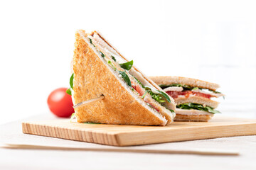 Grilled and pressed toast with cheese, tomato and lettuce served on wooden cutting board. Front...
