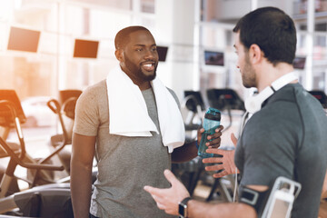 Two men communicate at racetracks in modern gym.
