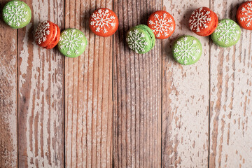 Christmas macaron border on a weathered wooden table background.  Iced with snowflakes these macaron macaroons are red and green and leave copy space and room for text.