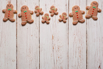 Christmas border with gingerbread cookies on a white weathered table background.  Cookies feature gingerbread men, women and children with copy space and room for text.