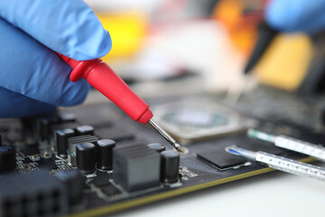 Gloved master holds probe over microcircuit. Repair and maintenance of e microcircuits concept