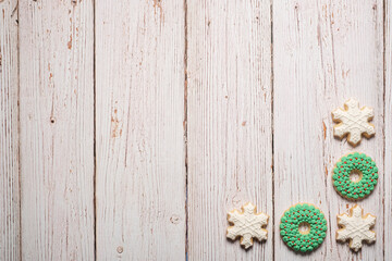 Christmas cookie border on a white weathered table background with copy space and room for text featuring sugar cookies with icing.