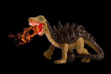 Fire breathing toy dinosaur. Children's toy, plastic animal figure isolated on black background,...