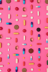 Creative layout of pills and capsules on pink background with summer sun and sharp shadow. Covid-19 or Coronavirus minimal art concept. Flat lay.