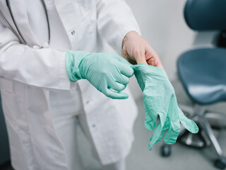 Junge Ärztin zieht sich vor der Behandlung Handschuhe an