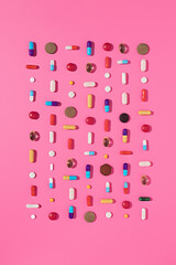 Creative layout of pills and capsules on pink background with summer sun and sharp shadow. Covid-19 or Coronavirus minimal art concept. Flat lay.