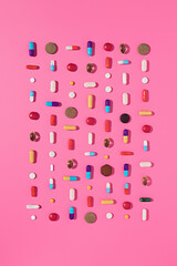 Creative layout of pills and capsules on pink background with summer sun and sharp shadow. Covid-19...