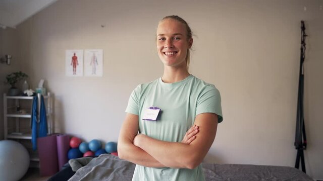 Portrait of a young confident female physiotherapist smiles and looks at camera standing in rehabilitation center