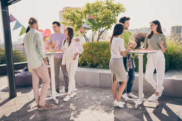 Full body portrait of beautiful fellows stand around table hands hold champagne talk listen meeting...