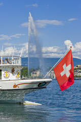 swiss flag on the stern of a vintage steamboat in the harbor with the water jet in Geneva,...